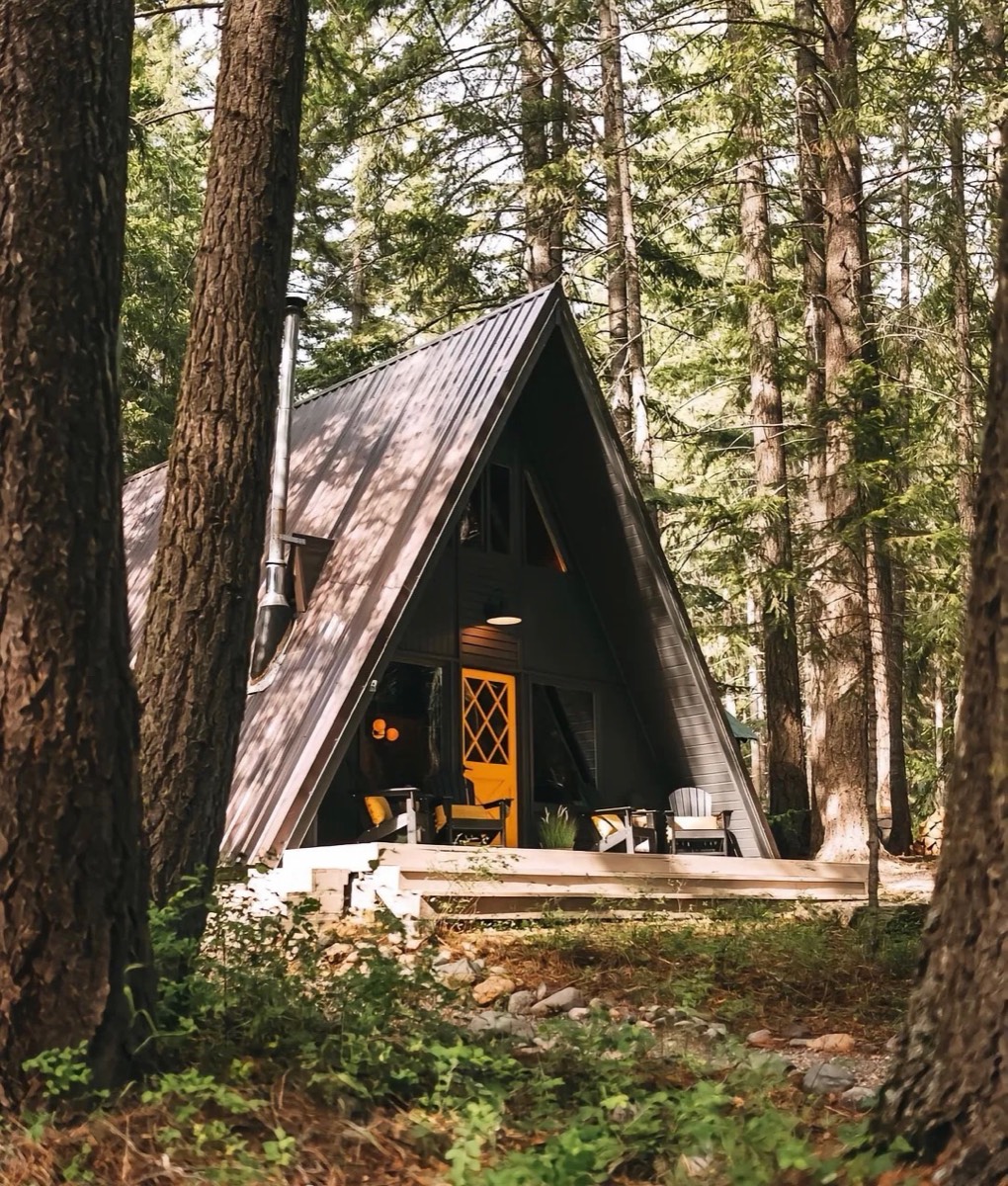 Angled exterior view of a dark woodland A-frame cabin