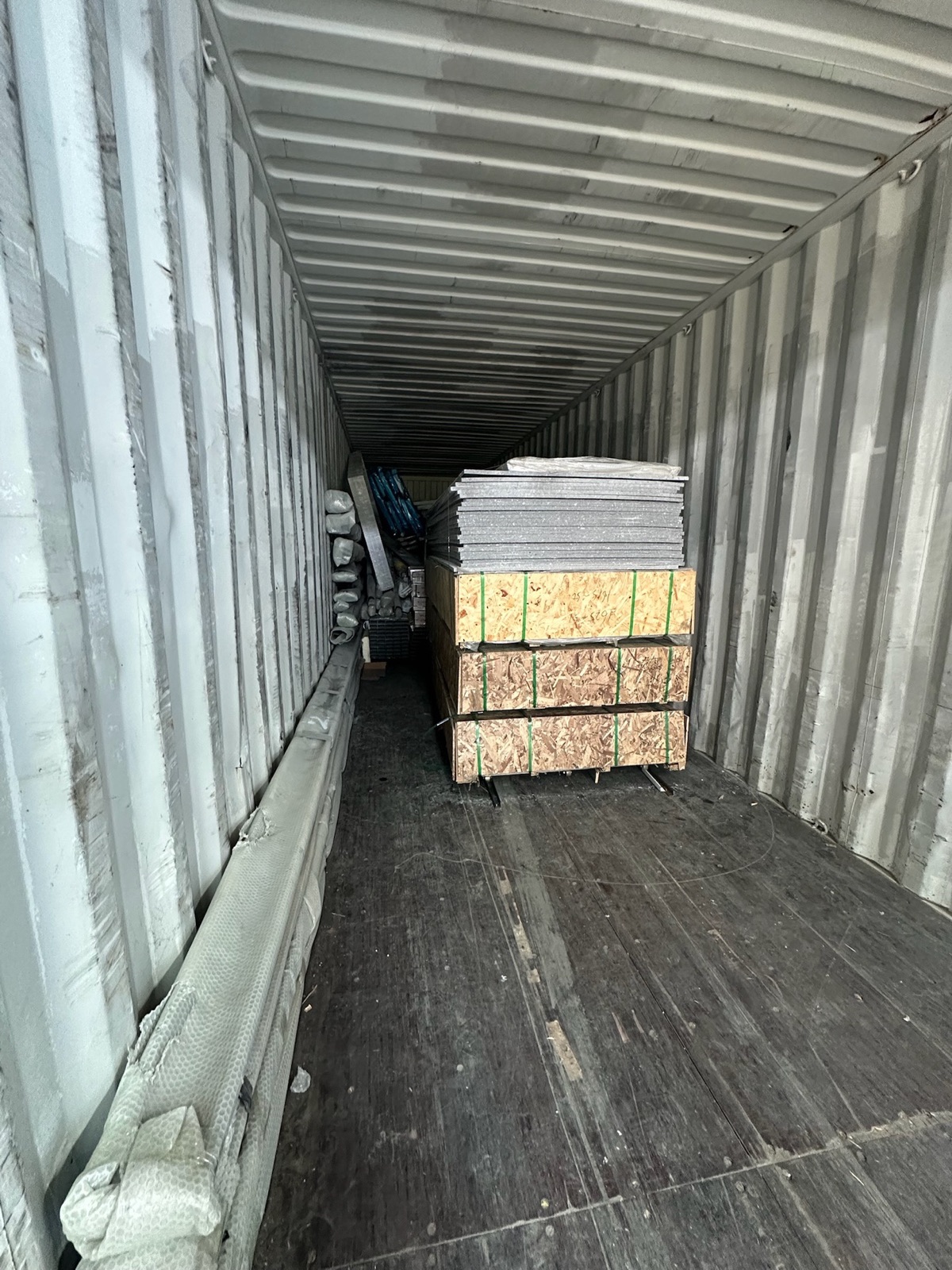 Crated modular wall panels and protected components loaded for sea freight