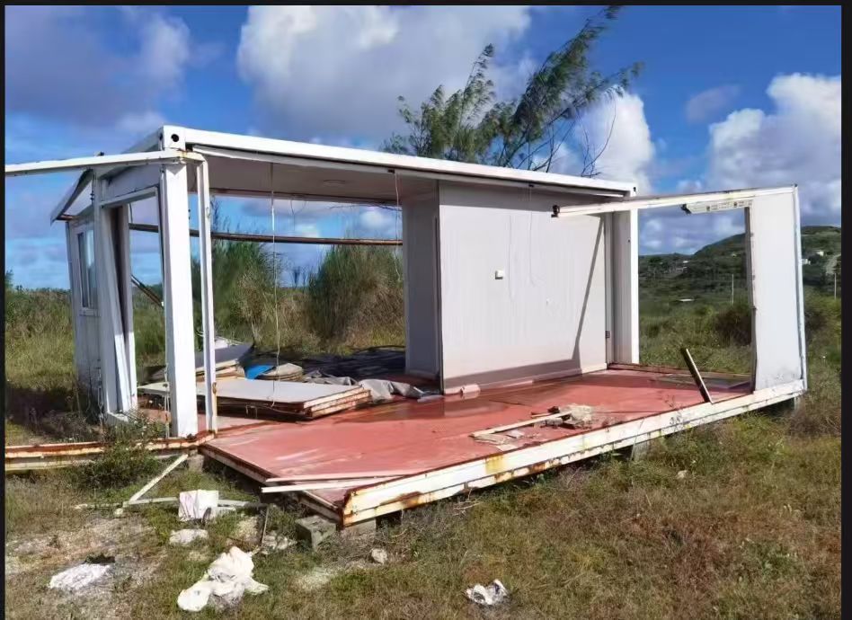 Post-storm structural damage visible on a lightweight prefabricated building