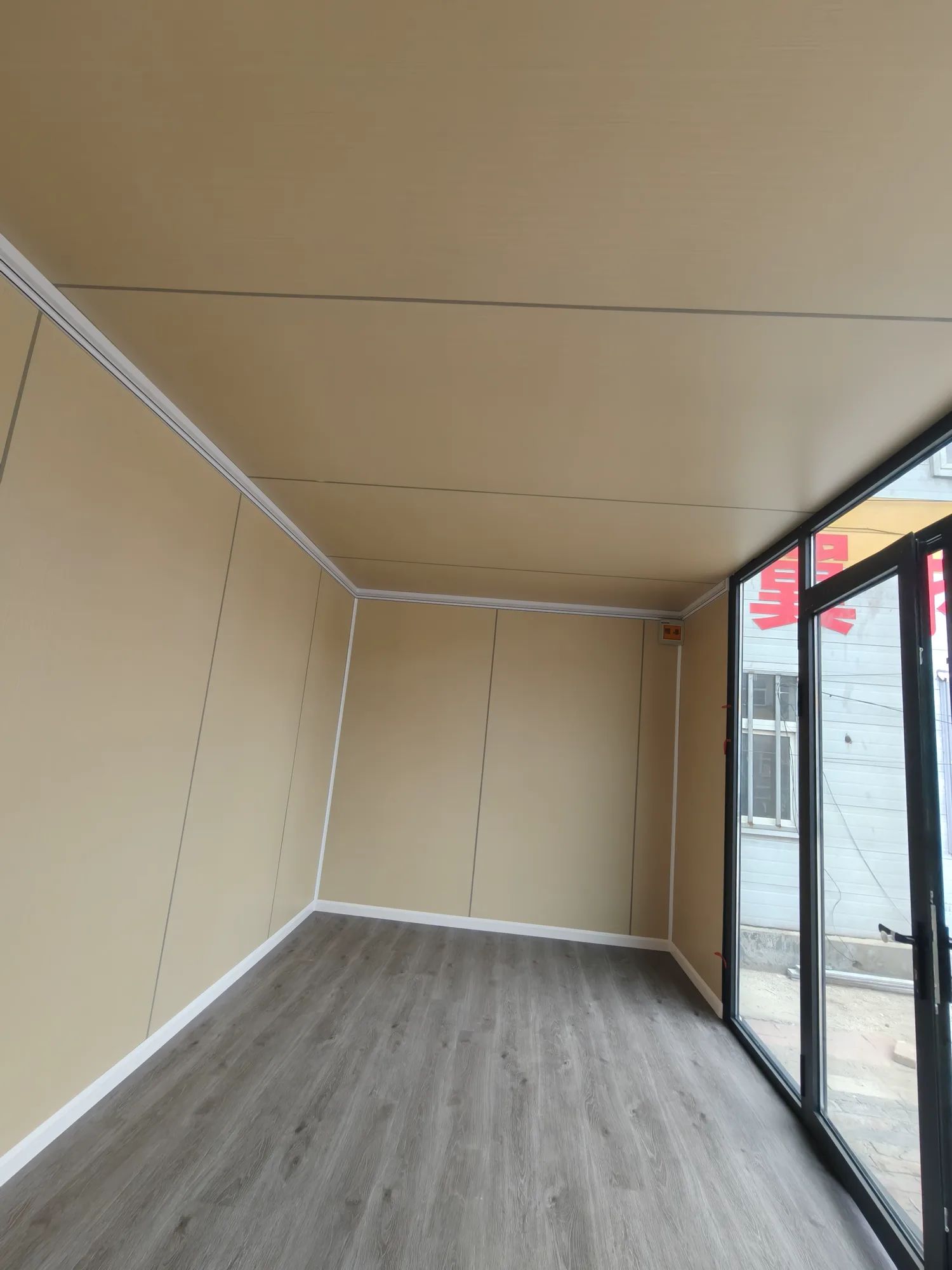 Unfurnished apple cabin interior with finished wall panels, flooring and full-height glazing